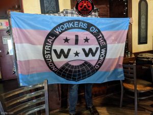 Akron wobbly holding up IWW trans right flag